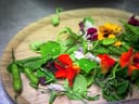 Essbare Blumen und Blätter auf einem Holzbrett.