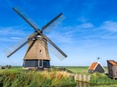 Traditionelle Windmühle in ländlicher Landschaft bei klarem Himmel.