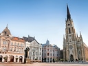Historische Gebäude und Kirche auf einem Platz bei klarem Himmel.