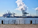 Hafenkräne am Ufer mit Fahrrad im Vordergrund.