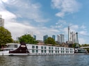 Passagierschiff auf Fluss vor städtischer Skyline.