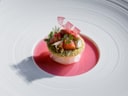 Gourmetgericht auf grossem weissen Teller mit rosa Sauce.