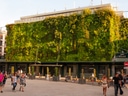 Gebäude mit grosser, grüner Pflanzenwand und Passanten.
