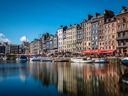 Bunte Häuser am Hafen mit Segelbooten und spiegelndem Wasser.