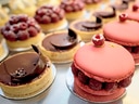 Nahaufnahme von verschiedenen eleganten Törtchen und Macarons mit Himbeeren.