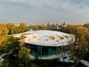 Moderne Architektur mit rundem Gebäude und Gründach inmitten von Bäumen.