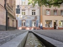 Schmale Wasserkanalstrasse mit historischen Gebäuden und Baum.