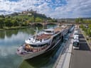 Flusskreuzfahrtschiff am Ufer mit Burg im Hintergrund.