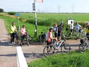 Gruppe von Radfahrern auf einem ländlichen Weg, umgeben von Feldern.