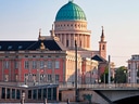 Historisches Gebäude mit Kuppel am Flussufer bei Sonnenuntergang.