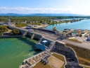 Luftaufnahme eines Staudamms mit Wasser, Strassen und angrenzender Landschaft.