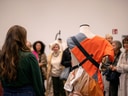 Personengruppe betrachtet modeinspiriertes Kunstwerk auf Schneiderpuppe.