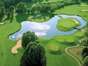 Luftaufnahme eines Golfplatzes mit Teich und Grünflächen.