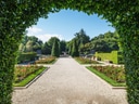 Garten mit gepflegten Wegen und Blumenbeeten, umgeben von Bäumen.