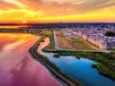 Luftaufnahme von einem Stadtrand bei Sonnenuntergang mit Flusslandschaft.
