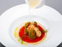 Gourmetgericht mit Gemüse und Sauce auf einem Teller angerichtet.