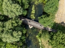 Luftaufnahme von Radfahrern auf einer Brücke über einen Fluss.