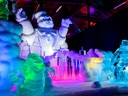 Bunte Eisskulpturen von Figuren und Gebäuden in einer Ausstellung.
