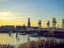 Sonnenuntergang über einer Brücke und Stadtansicht mit Kirchturm.
