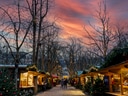 Weihnachtsmarkt mit Lichtern bei Sonnenuntergang.