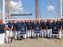 Gruppe von Männern in Uniform vor einem Segelschiff.