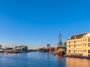 Wasserblick auf Gebäude und Schiff unter blauem Himmel.