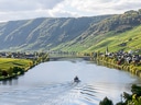 Flusslandschaft mit Boot, Hügeln und Weinbergen.