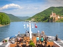 Passagierschiff auf Fluss mit Schloss im Hintergrund.
