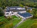 Luftaufnahme eines historischen Gebäudekomplexes umgeben von Bäumen und Gärten.