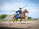 Reiter in traditioneller Kleidung auf Pferd mit Peitsche.