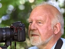 Älterer Mann mit Kamera im Freien.