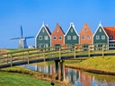 Bunte Häuserreihe mit Windmühle und Brücke über Kanal.