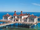 Historische Seebrücke über dem Meer, mit roten Dächern und türkisfarbenem Wasser.