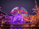 Beleuchteter Themenpark mit geodätischer Kuppel und leuchtenden Bäumen bei Nacht.