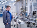 Mann arbeitet an einer Maschine in einer Fabrik.