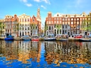 Farbenfrohe Häuser am Amsterdamer Kanal mit Booten.