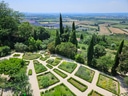 Blick auf geometrischen Garten mit Zypressen und Landschaft im Hintergrund.