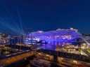 Beleuchtetes Kreuzfahrtschiff bei Nacht im Hafen.