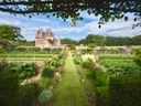 Historischer Garten mit Schloss im Hintergrund.