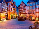 Historischer Platz mit Fachwerkhäusern bei Abenddämmerung.