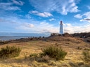 Leuchtturm auf einem Hügel mit Blick auf das Meer.