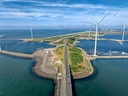 Luftaufnahme einer Küstenstrasse mit Windkraftanlagen.
