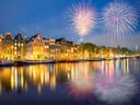 Feuerwerk über einem Kanal mit beleuchteten Häusern.