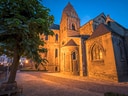 Abendansicht einer beleuchteten historischen Kirche mit Bäumen im Vordergrund.