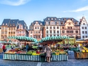 Bunter Marktplatz mit historischen Gebäuden im Hintergrund.