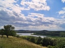 Landschaft mit Fluss, Hügeln und Wolkenhimmel.