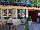 Aussenszene eines Cafés mit bemaltem Mauerwerk, Tischen und Stühlen auf Pflastersteinen.