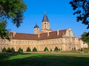 Historische Abtei mit Türmen und grünem Innenhof.