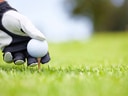 Golfer hand setzt Ball auf Tee im Gras.