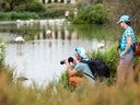 Mann und Frau beobachten Flamingos an einem Teich.